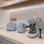 Light blue toaster, kettle, and espresso machine on a white kitchen countertop.