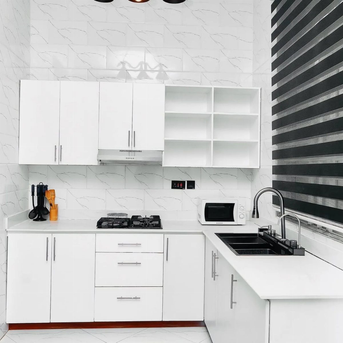 White kitchen cabinets with white countertops and a patterned white tile backsplash.
