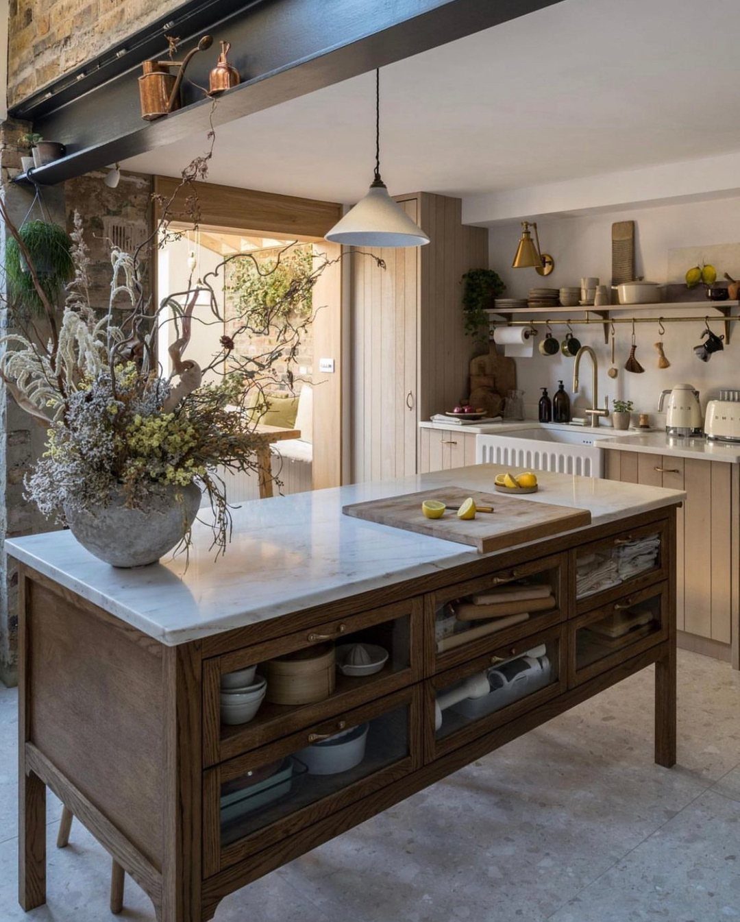 Wooden farmhouse kitchen island with marble top and glass drawers in rustic kitchen