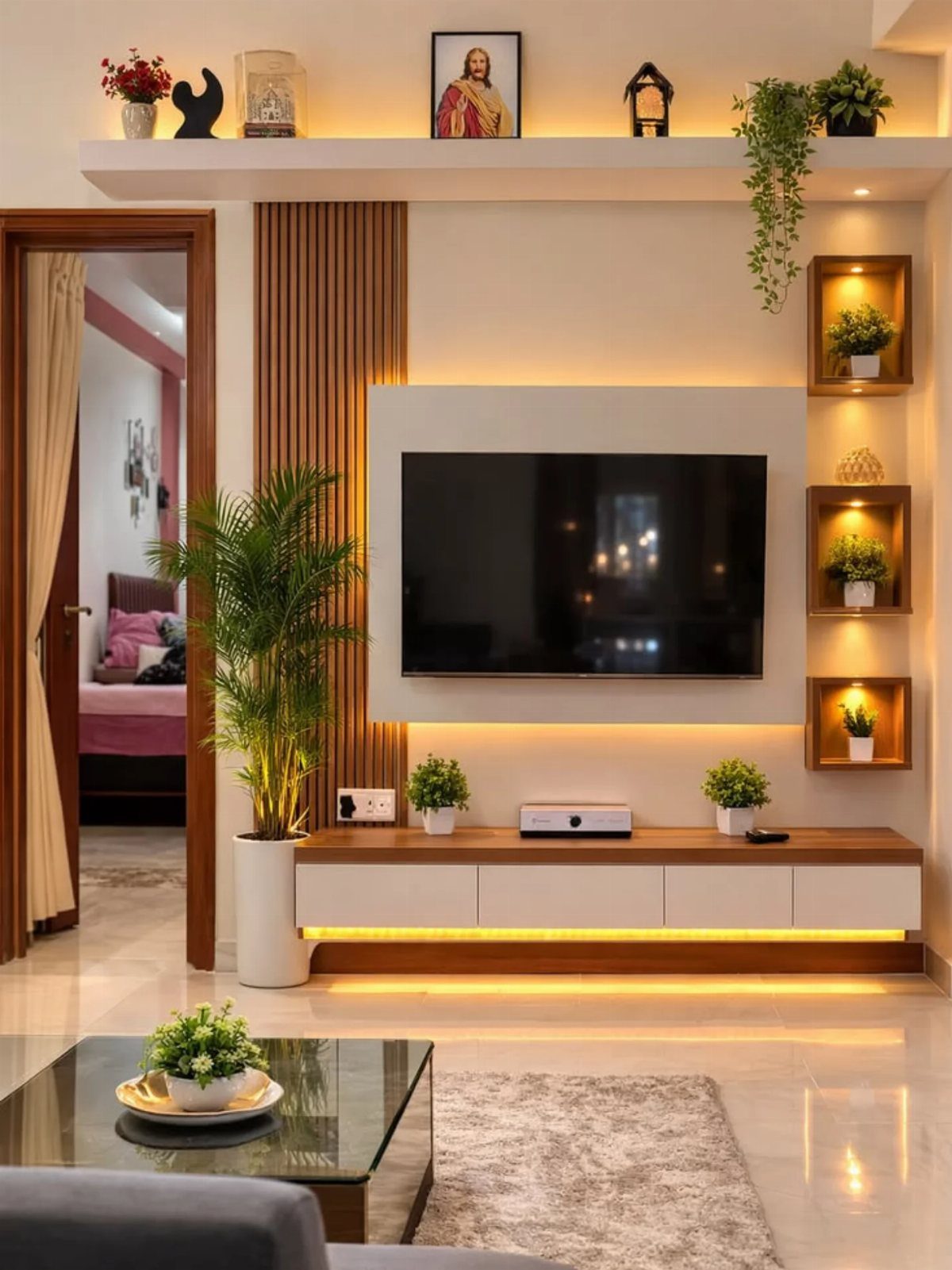 Modern living room wall with integrated shelving, a television, and warm LED lighting.